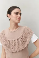 Chaleco color crema de tejido de punto, con cuello redondo y volados de crochet en el frente y la espalda.