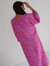 Vestido midi de corte holgado con estampado floral en tonos rosa y naranja, escote en V y mangas cortas amplias.
