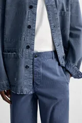 Pantalón azul de corte recto, con cintura ajustable, bolsillos laterales y traseros, y bolsillo tipo plastrón en la pierna. Tiene un lavado vintage con efecto de manchas.
