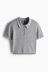 Remera polo corta de punto fino color gris con cuello, tapeta de botones y mangas cortas con ribete blanco.