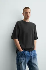 Camiseta negra de corte holgado, cuello redondo y mangas cortas. Tiene un efecto de lavado que le da una apariencia única.