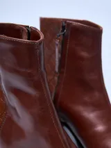 Bota de cuero color marrón con tacón cuadrado y diseño moderno.
