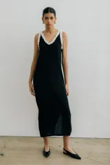 Vestido midi negro con escote en V, breteles finos con volados blancos y tajos laterales.