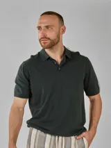 Remera de punto de manga corta, color verde oscuro, con cuello polo y cierre parcial de botones.
