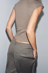 Top sin mangas, color marrón topo, con cuello alto y corte recto. Presenta un tejido de punto fino y mangas sisa con caída.