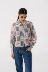Camisa blanca estampada con cartas de juego en tonos pastel, de corte cropped y mangas largas.