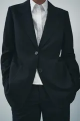 Blazer recta negra de Zara Woman Collection, con cuello solapa, manga larga con abertura y botones, bolsillos de plastrón en delantero, forro interior a tono y cierre frontal con botones.