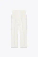 Pantalón blanco de tiro alto con bolsillos delanteros y falsos bolsillos de vivo en la espalda. Tejido con efecto arrugado, pernera recta y cierre frontal con cremallera, botón interior y gancho.