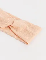Vincha elástica texturada color salmón con nudo torzado.