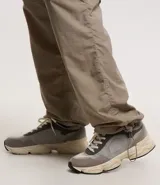 Pantalón paper touch color verde militar, con bolsillos laterales, cintura elástica y cordón de ajuste. Se convierte en bermuda gracias a un cierre a la altura de la rodilla.