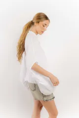 Camisa celeste de lino con corte amplio, cuello mao y mangas cortas. Presenta cierre frontal con botones y ribete negro en cuello y tapeta.