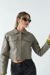 Sobrecamisa cropped de cuero sintético color negro, con cuello clásico, cierre frontal con botones, mangas largas y bolsillos frontales con solapa.