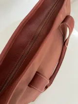 Bolso tote negro de lona con apliques de cuero y doble asa de mano.