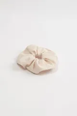 Scrunchie de tela color crudo con textura.