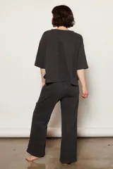 Pantalón de corte relajado color negro con efecto lavado, confeccionado en mezcla de algodón orgánico. Presenta una cintura elástica para mayor comodidad y bolsillos superpuestos a la altura de las rodillas, fusionando un estilo utilitario con el confort de una prenda de ocio.