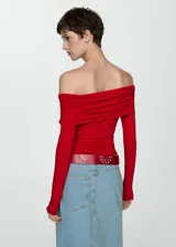 Camiseta roja con hombros descubiertos, cuello con volantes, mangas largas y corte ajustado.