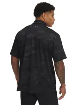 Chomba de golf Under Armour Playoff Polo 3.0 negra con estampado camuflado en tonos oscuros y logo de la marca en el pecho.
