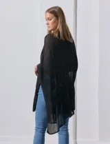 Poncho negro de tejido calado con lurex, terminación asimétrica y cuello redondo.