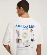 Remera de algodón blanca, corte oversized, con estampa gráfica en la espalda que incluye un teléfono antiguo, un CD, una cámara fotográfica, auriculares y un reproductor de CD portátil, junto al texto "Analog Life - NO EDITS -".