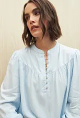 Camisa celeste de manga larga en viscosa suave, con cuello mao y botonadura parcial al frente. El detalle de frunces en los hombros y los puños abotonados le suman delicadeza y estilo.