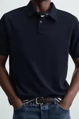 Polo de piqué color crudo, corte regular fit, cuello solapa con cierre de botonadura y mangas cortas.