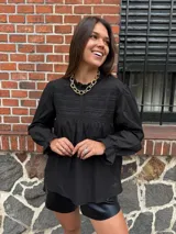 Camisa blanca de mangas largas con detalles de encaje en el cuello y el pecho.