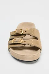 Sandalia plana color beige de serraje con doble tira delantera y hebillas.