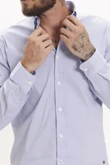 Camisa celeste a rayas verticales, de corte clásico, con cuello abotonado y mangas largas.