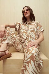 Camisa de manga corta color beige con estampado de hojas blancas, de corte recto y cuello camisero.