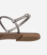 Sandalia plana dorada con tiras finas y aplicación de pedrería.