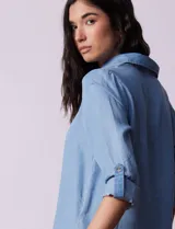 Blusa celeste en lyocell, con cuello a la base con solapa, escote en V y abertura central con botones. Manga larga regulable con presilla y botón.