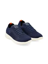 Sneaker azul marino de tejido de punto con cordones elásticos, suela blanca de goma y tirador naranja en el talón.