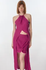 Conjunto de top halter con abertura en el abdomen y falda cruzada con ruedo desflecado, color fucsia.
