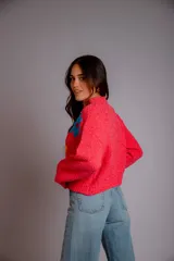 Buzo de punto color lila, con cuello redondo, mangas largas y diseño holgado. Presenta tres flores bordadas en el frente: una rosa claro, una azul y una amarilla con centro azul.