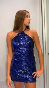 Vestido corto ajustado, color azul eléctrico, con cuello halter y completamente cubierto de lentejuelas.