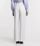 Pantalón blanco de crepé, corte recto, con trabillas en la cintura, cierre con botón y cremallera, y colgante de corazón metálico.