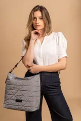 Bolso tipo shopper color beige con diseño acolchado geométrico y correa de hombro negra.