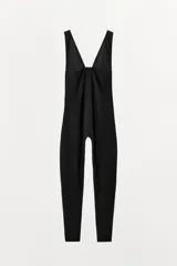 Mono largo negro, de corte ajustado, con escote pico pronunciado y tirantes anchos. Presenta un cierre frontal con cremallera oculta.