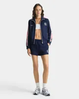 Campera deportiva azul marino con cierre frontal, cuello alto y puños acanalados. Presenta el logo de los Yankees bordado en blanco en el pecho y detalle de tres rayas rojas y blancas en las mangas.