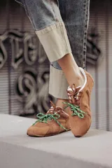 Zapatillas urbanas de cuero color tostado, con cordones verdes y suela de goma.