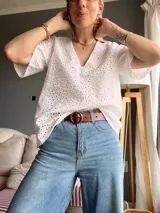 Blusa blanca de broderie con escote en V y mangas cortas amplias.