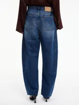 Pantalón denim azul de corte amplio, tiro alto, con bolsillos delanteros y traseros, y terminación desflecada en el bajo.