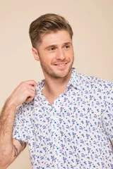Camisa celeste con estampado floral blanco, de manga corta y corte clásico. Cierre frontal con botones.