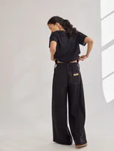 Pantalón negro de tiro medio alto con pretina elastizada en la espalda, pierna ancha y bolsillos plaque en delantera y espalda.