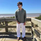 Camisa de manga larga color blanco, con textura de lino arrugado, cuello camisero y botones frontales.