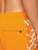 Short de baño naranja con estampado de monogramas TH en blanco a lo largo de la pierna.