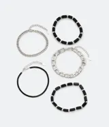 Set de cinco pulseras para hombre, con dos pulseras de cadena plateada de diferentes grosores, una pulsera de cuentas negras con detalles plateados, una pulsera de cuentas negras facetadas y una pulsera de cadena negra.