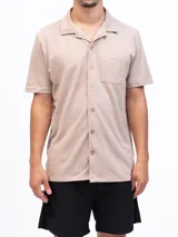 Camisa de manga corta color beige, confeccionada en tejido piqué de algodón, con cuello cubano y un bolsillo de parche en el pecho.