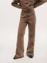 Pantalón de denim verde oliva con efecto gastado, corte recto, tiro medio y botones metálicos en el lateral inferior.