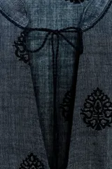 Blusa azul con bordados negros, cuello redondo con escote en pico y cordones ajustables terminados en borlas.